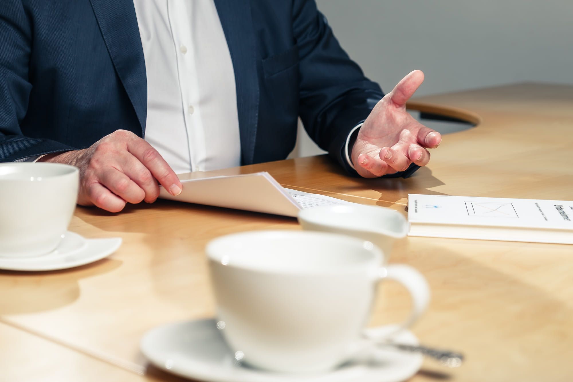 Besprechung am Tisch, zwei Tassen und Unterlagen davor