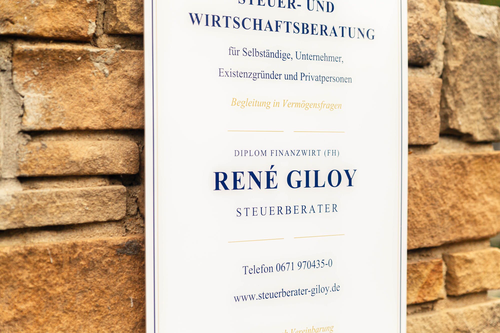 Schild der Kanzlei an der Klinkerfassade mit Anschrift und Telefonnummer