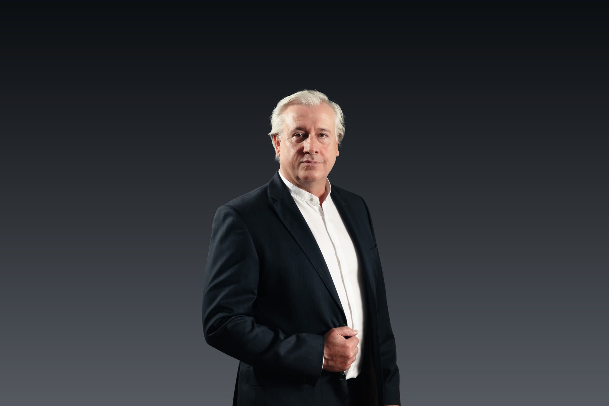 René Giloy im Sakko vor dunklem Hintergrund