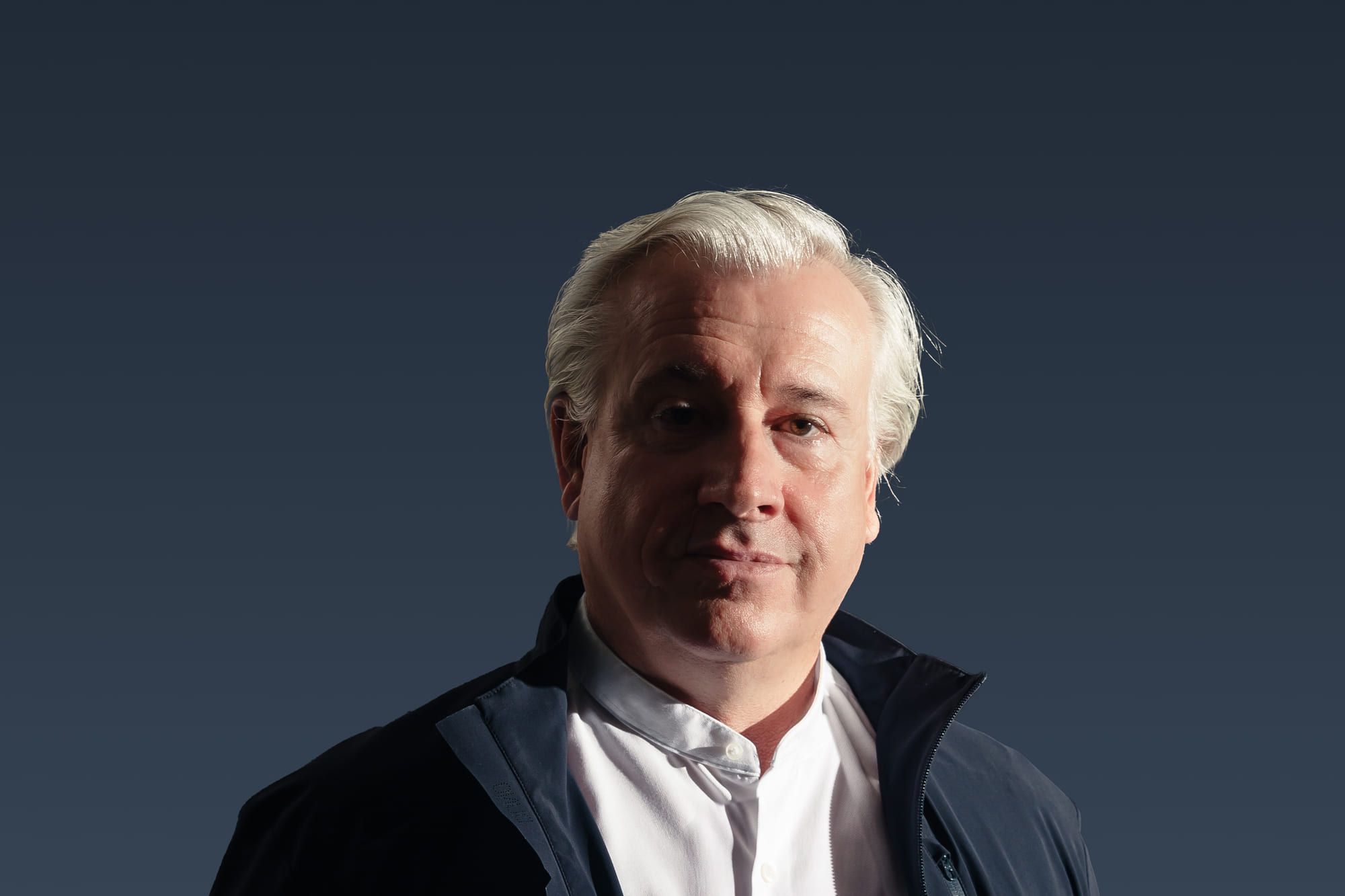 René Giloy in dunkelblauer Jacke vor dunkelblauem Hintergrund
